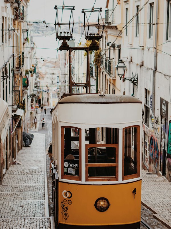 Yellow tram beside tiled buildings in Lisbon