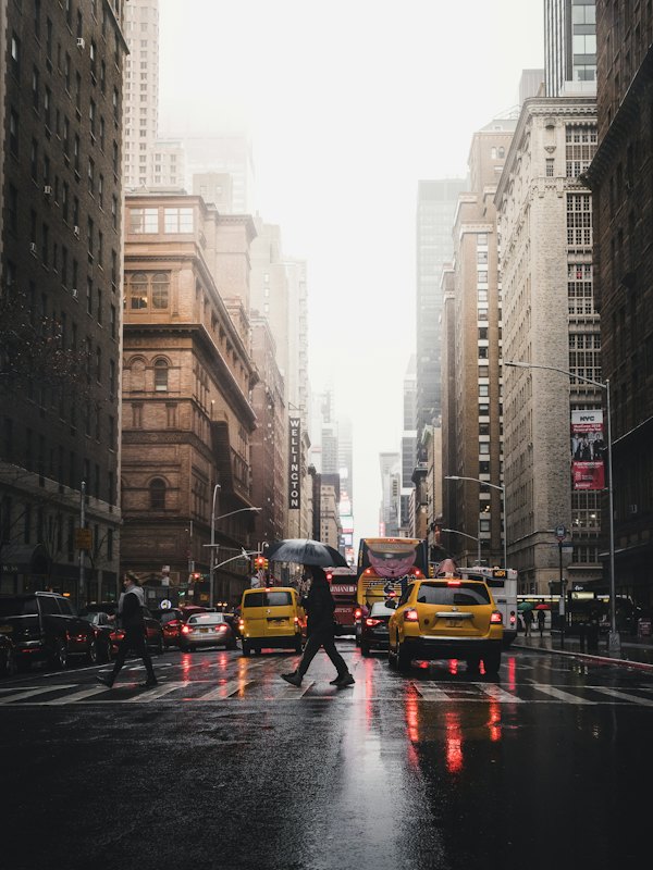 Person crossing a street between tall buildings in New York